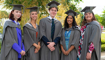 five students wearing graduation gowns